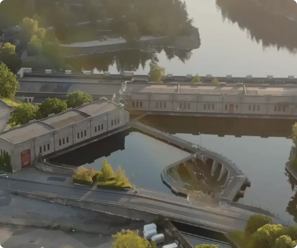 Drone view of facilities, greenery and water.